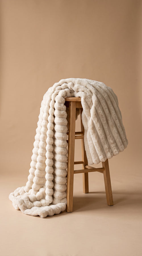 Plaid Pelage crème jeté sur un tabouret